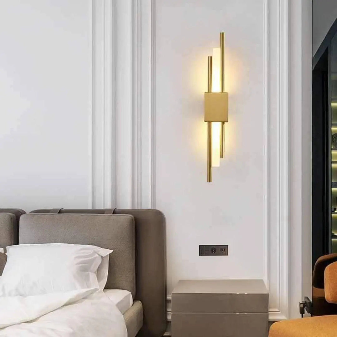 Applique murale design LED en laiton doré pour salon, moderne et élégante, montée verticalement sur un mur.
